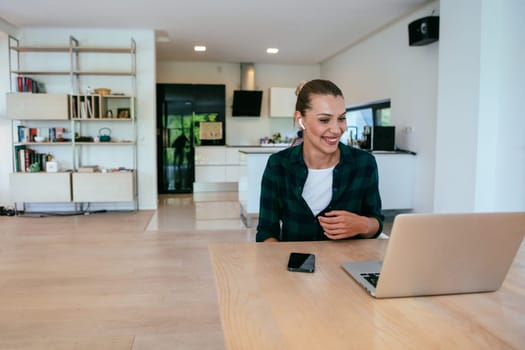 A woman sitting in the living room using a laptop is looking at cam talk by video call with business friends and relatives. The headshot is Job interview answering questions.