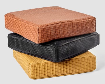 Three square cushions made of woven leather are stacked, creating a stylish and comfortable seating arrangement