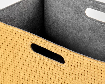 Close-up of an empty yellow woven storage box with grey felt lining and convenient carry handles