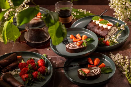 Delicious chocolate swiss rolls and fresh strawberries elegantly arranged on plates, accompanied by glasses of iced coffee, creating a tempting dessert scene