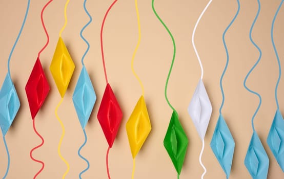 A row of multicolored origami paper boats with corresponding colored wavy lines on top, symbolizing individual paths or connections