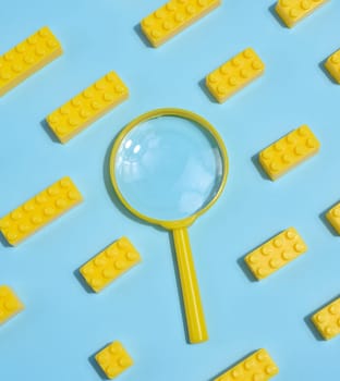 A yellow magnifying glass is surrounded by yellow toy cubes on a blue background.