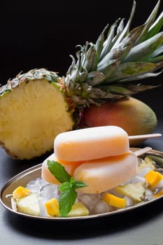 Enjoy a delicious treat featuring mango pineapple ice cream placed atop ice with chunks of fresh pineapple. Garnished with mint, this dessert exudes summer vibes.