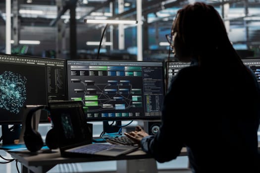 Data center software developer looks at AI visualization dashboard to pinpoint equipment performance issues. Server farm expert looks at node tree and data analysis graph on computer