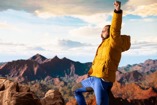 Happy adventurer embraces the thrill of standing at the top of the mountain, feeling the power of accomplishment. Awe inspiring mountain range with peaceful sky and vast wilderness.
