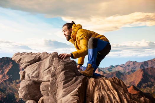 Determined climber standing at the summit enjoys peaceful moment of success. Vast sky, mountain range and fresh air highlighting the essence of freedom, wellness and exploration.
