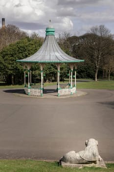 Newcastle, UK - Apr 13, 2025 - View of A Bandstand And A Grandstand. It’s a modern replica of the Victorian bandstand that had been installed in the Leazes park. The Music Pavilion with Green trees in the background, use it as your Wallpaper, Poster and Space for text, Selective focus.