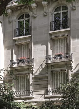 France, Paris - May 03, 2025 - Stunning view of Traditional French residential tenement building with Traditional French Shutters & Windows and wrought iron black railings balconies located in the center of Paris. Facade of the Parisian building. use it as your Wallpaper, Poster and Space for text, Selective focus.