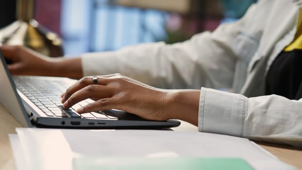 Freelancer in home office sitting at desk and typing on laptop keyboard. Close up of remote worker using electronic device to do customers relations job online, answering inquiries, camera B