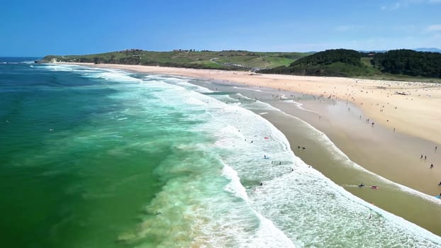 A stunning aerial view beautifully showcases a picturesque beach featuring golden sands and vibrant ocean waves