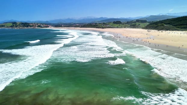 A beautiful and picturesque beach scene with gentle waves, lush green hills, and happy people enjoying the warm sun