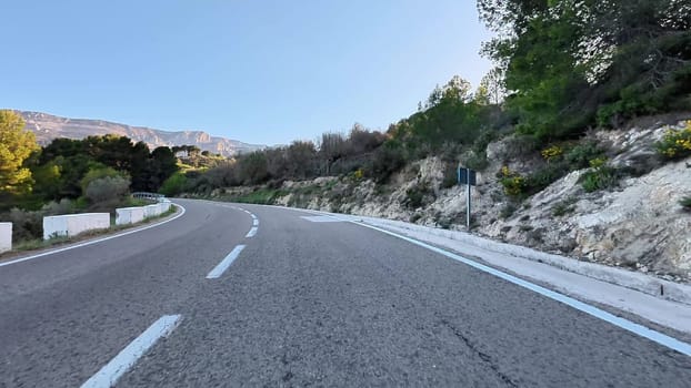 A breathtakingly picturesque view of a winding road embraced by lush greenery and majestic hills in the background