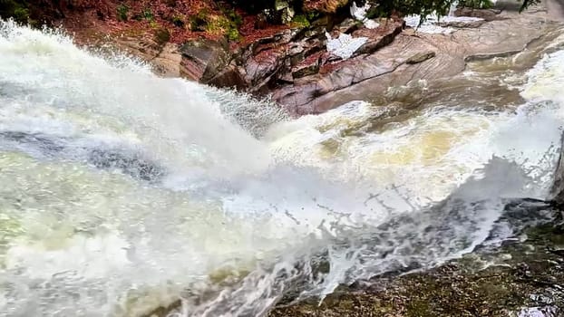 Experience breathtaking views of a magnificent waterfall cascading over rocky terrain surrounded by vibrant greenery