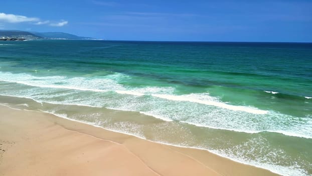 Picture a serene tropical beach featuring clear blue waters and gentle waves rolling in under a bright sunny sky