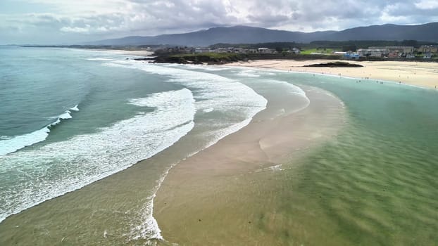 Stunning aerial view presenting waves gently lapping against a beautiful, sandy beach amid a picturesque backdrop