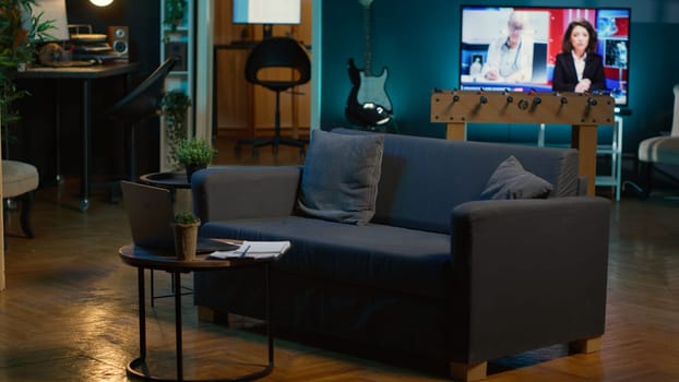 Stylish modern apartment decorated with cool furniture and neon lights, home theatre and setup with big tv for a young adult. Empty loft illuminated and equipped with electronics, comfortable space.