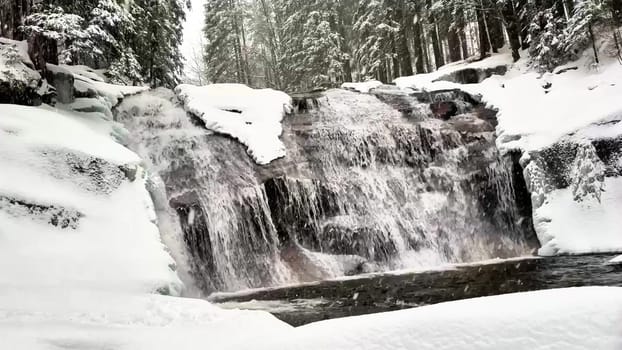A breathtaking winter waterfall flows gracefully through a peaceful, snowcovered landscape in natures embrace