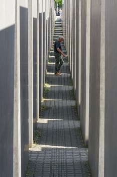 Berlin, Germany – May 01, 2025: Visitor between the concrete blocks at the Holocaust memorial in downtown Berlin