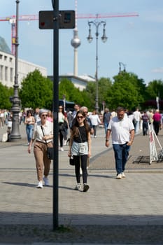 Berlin, Germany – May 01, 2025: Tourists on Pariser Platz in front of the Brandenburg Gate in the center of Berlin. The television tower in the background.