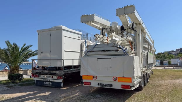 Budva, Montenegro - May 18, 2025: Ferris wheel cabins are folded on truck beside scenic waterfront view