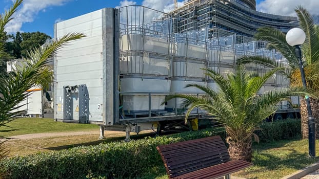 Budva, Montenegro - May 18, 2025: Transport trailer carrying folded ferris wheel cabins surrounded by palm trees