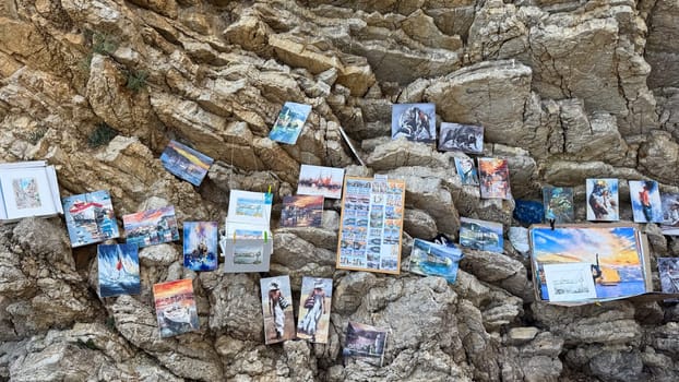 Budva, Montenegro - May 18, 2025: An art exhibition on a rocky cliff near Mogren Beach, displaying various paintings and scenic views.