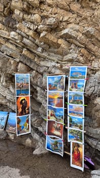 Budva, Montenegro - May 18, 2025: Colourful paintings displayed on a rock wall near Mogren Beach.
