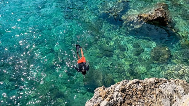 Budva, Montenegro - May 18, 2025: Male snorkeler explores vibrant underwater world near rocky coast