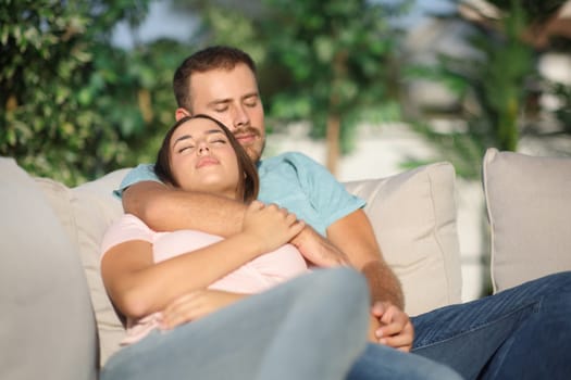 Couple sleeping sitting in a comfortable exterior sofa in a terrace at home
