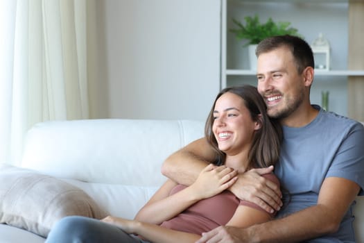 Happy couple hugging and relaxing sitting on a couch at home