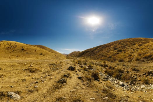 dry river bed between hills and clear blue sky above at sunny autumn day