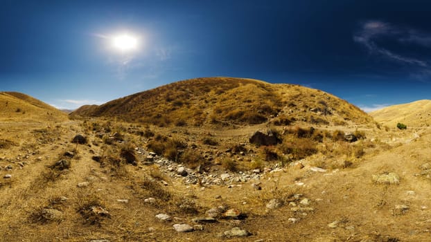 dry river bed between hills and clear blue sky above at sunny autumn day