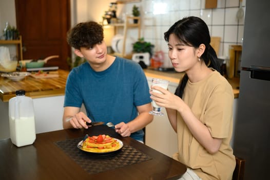Romantic couple enjoying pancake breakfast together in a cozy kitchen.