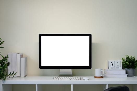 Minimal home office with desktop monitor on white desk with calendar.