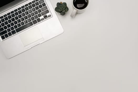 Overhead image of a tidy desk with laptop, a cup of coffee, and plant.