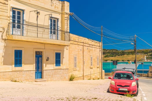 A typical Maltese house with a red car parked in front of it, Marsaxlokk, Malta.