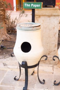 Decorative bin for paper waste outdoors with a sign. Concept of waste sorting and recycling for public areas. Environmental responsibility and sustainable practice promoting eco-friendly disposal