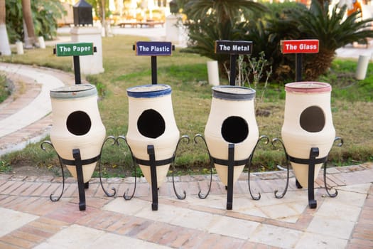 White ceramic outdoor recycling bins specifically for sorting paper plastic metal glass. Environmental waste management concept for public areas and hotels seeking sustainability