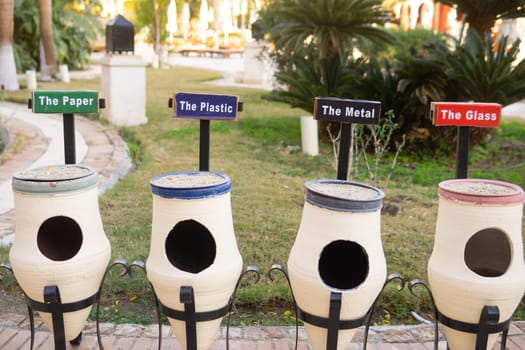 White ceramic outdoor recycling bins specifically for sorting paper plastic metal glass. Environmental waste management concept for public areas and hotels seeking sustainability