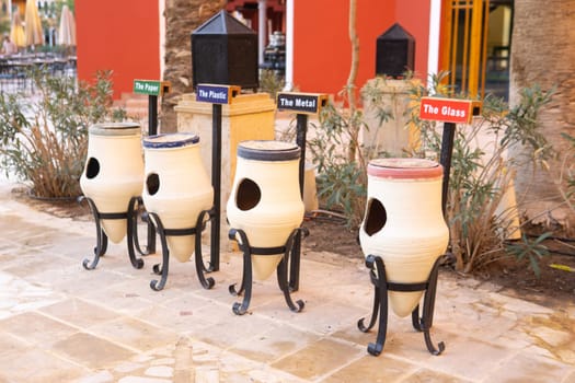 White ceramic outdoor recycling bins specifically for sorting paper plastic metal glass. Environmental waste management concept for public areas and hotels seeking sustainability