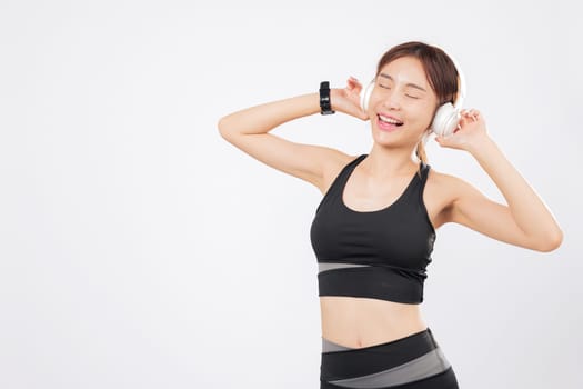 Dance expresses freedom for this cheerful Asian woman in workout gear. As music flows, she moves again to dance with confidence and a smile on her face. isolated studio white background