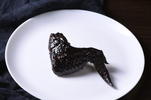 Bat wings. Cooked in sweet and sour sauce with cuttlefish ink, served with ketchup on a plate. An original idea for a Halloween party