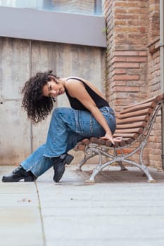 African American woman dancing in a creative pose between benches in an urban setting. he wears casual clothes and shows balance,strength, and expression. Concept of movement, art,and freedom.Vertical