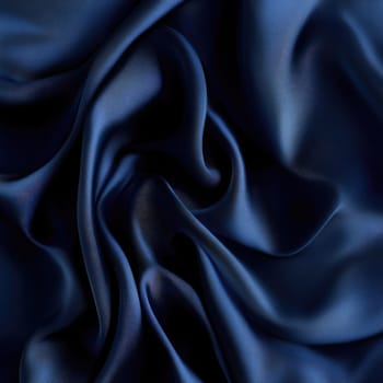 Soft and smooth deep blue silk fabric is arranged in gentle folds, highlighting its luxurious texture and sheen under natural light, creating an elegant visual appeal.