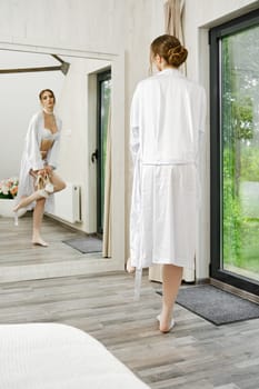 Stylish woman looking at her reflection in large wall mirror while dressing