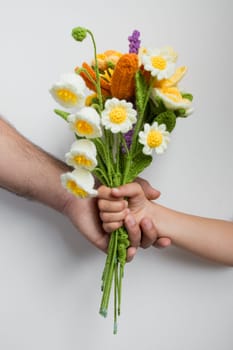 Child handing crocheted flower bouquet to adult. Father day concept.