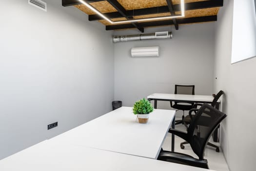Bright and inviting workspace with sleek white desks and ergonomic chairs, perfect for productivity. Green plant adds a touch of nature to the minimalist decor.