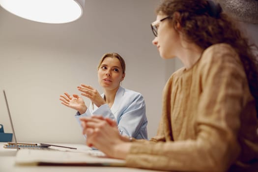 Two women share innovative ideas in a modern office, showcasing thoughtful discussion and collaboration