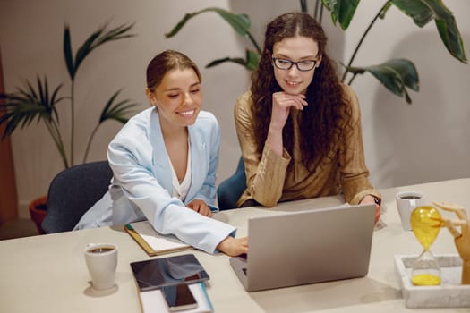Two professionals engaged in a productive discussion while collaborating over a laptop in a modern office