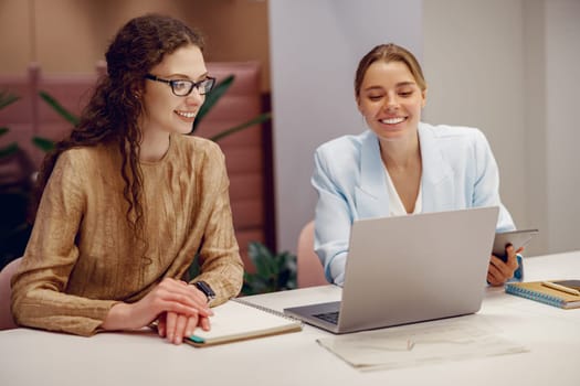 Two women in a productive meeting, confidently sharing innovative ideas and using advanced technology